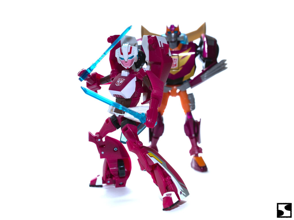 Arcee holding two swords with Rodimus at the back