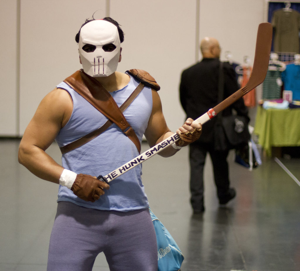 Casey Jones in blue sleeveless shirt and wears a full-face white mask