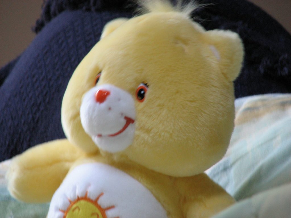 Funshine Bear, a yellow Care Bear, with a smiling golden sun on his tummy