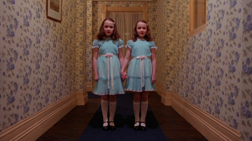 twin girls holding hands in the middle of a hallway