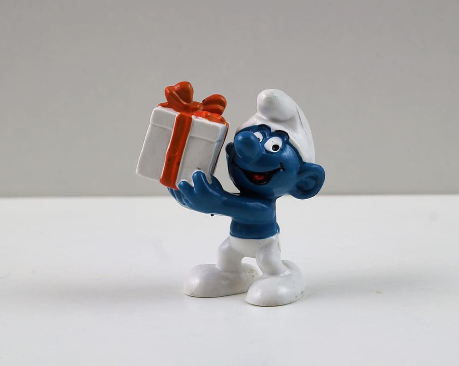 Jokey Smurf in white hat and pants, smiling while holding a gift
