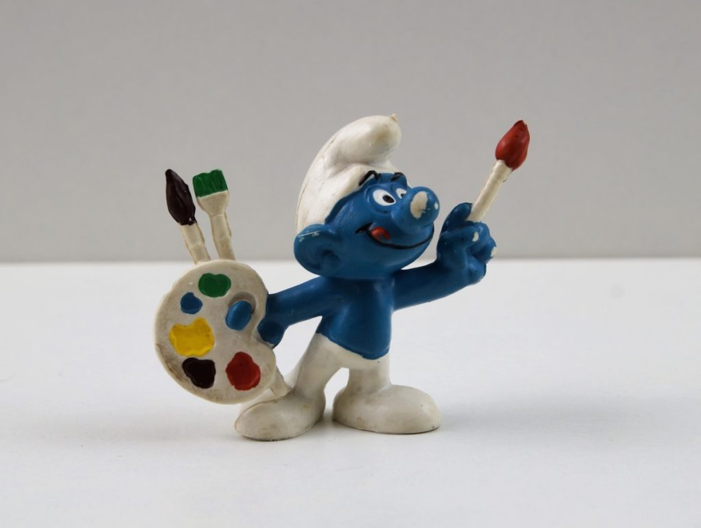 Painter Smurf holding a color palette and paint brushes