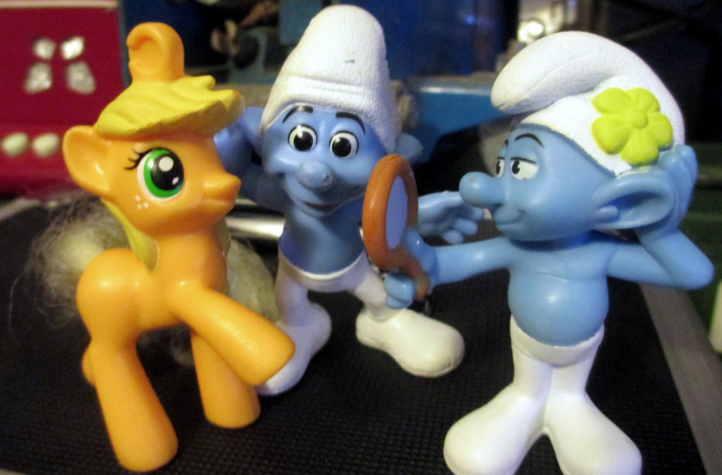 Vanity Smurf with a flower on his hat and carries a mirror together with Crazy Smurf and Applejack