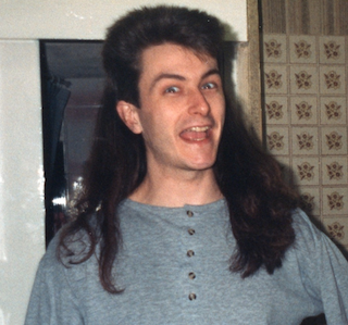 A smiling man in a Mullet hairstyle