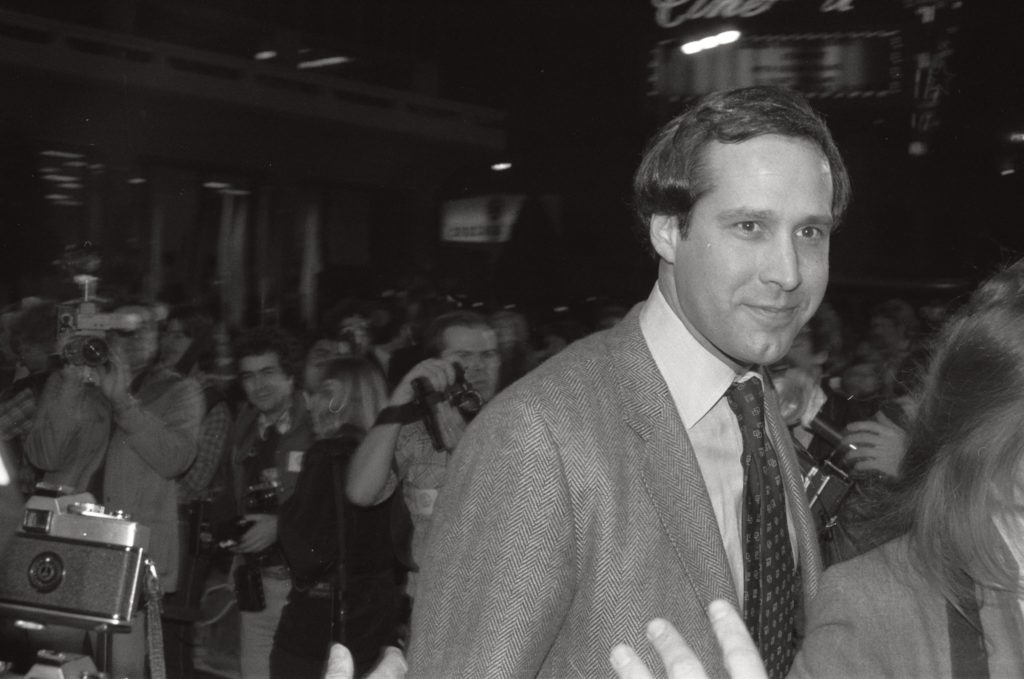 Chevy Chase, from Spies Like Us, in crowded space with lots of photographers