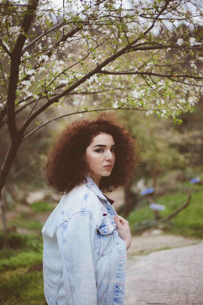 An afro-haired woman wearing an acid-washe denim jacket