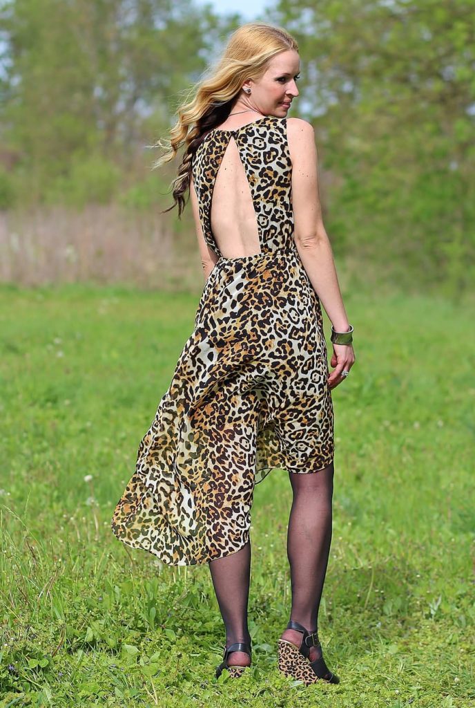 A woman wearing an animal print dress while standing on a grassland