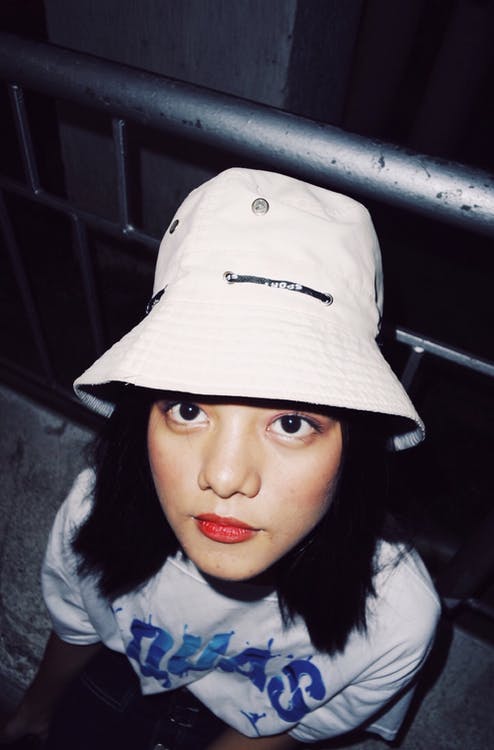A woman wearing a white bucket hat while looking up