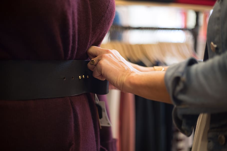 A person fixing another person’s corset belt