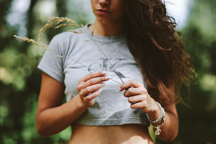 curly-haired woman wearing a gray cropped top