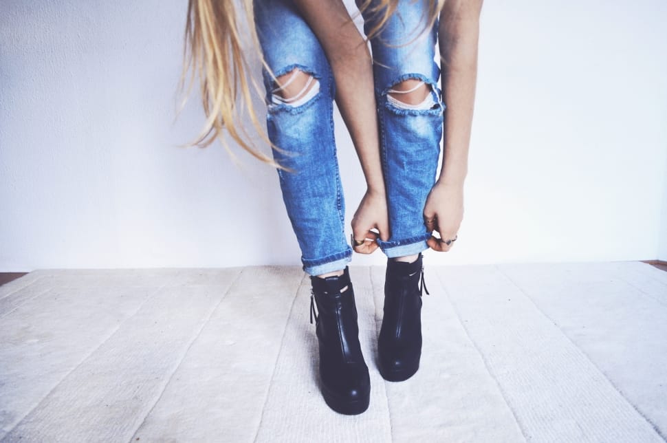 A woman folding the ends of her distressed jeans