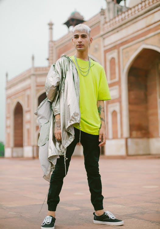 A man wearing a neon shirt layered with a silver-colored windbreaker