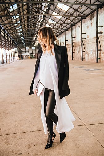 A woman wearing a black oversized blazer while standing in the middle of a walkway