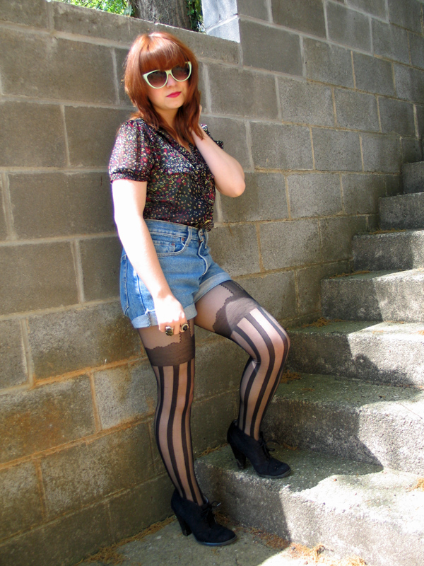 A woman wearing black sheer tights topped with denim shorts
