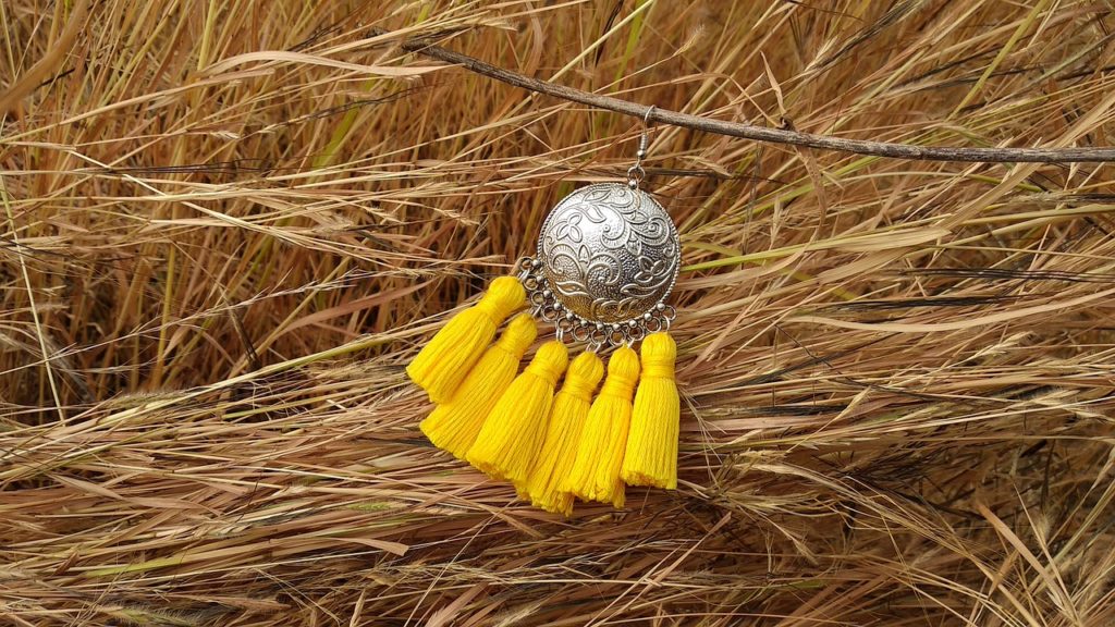 A yellow tassel earring displayed in the middle of a rice fiel