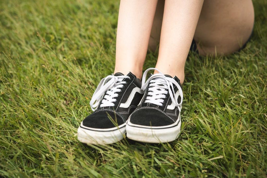 A pair of worn Vans shoes stepped on a grassland