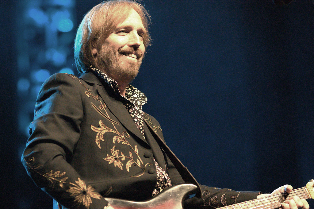 Tom Petty plays electric guitar on stage