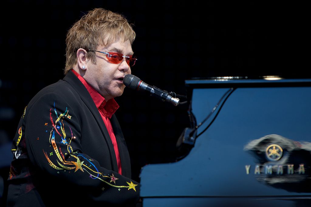 a man singing while playing piano on stage