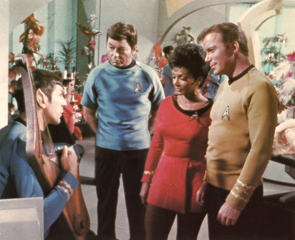 Kirk and Uhura looking at a man in a scene from Star Trek