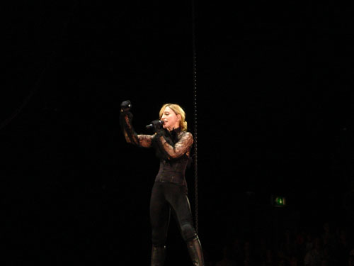 a woman singing on stage wearing all black